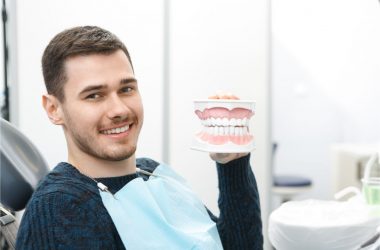 The patient holds an artificial teeth model.